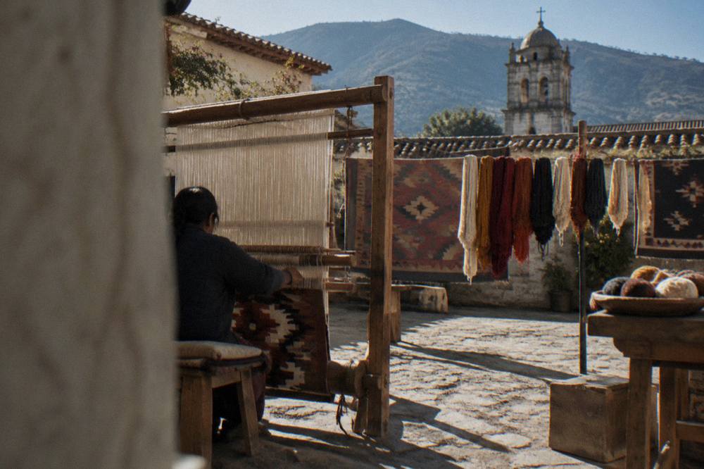 A weaver working a large wool rug on a foot loom in a village workshop near Oaxaca