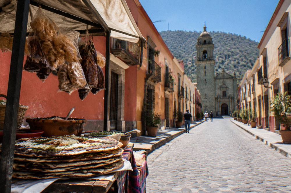 A market food stall in Oaxaca with stacked tlayudas and hanging snacks