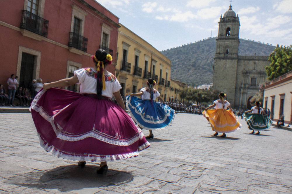 Festival dancers in traditional dress performing in an Oaxaca square