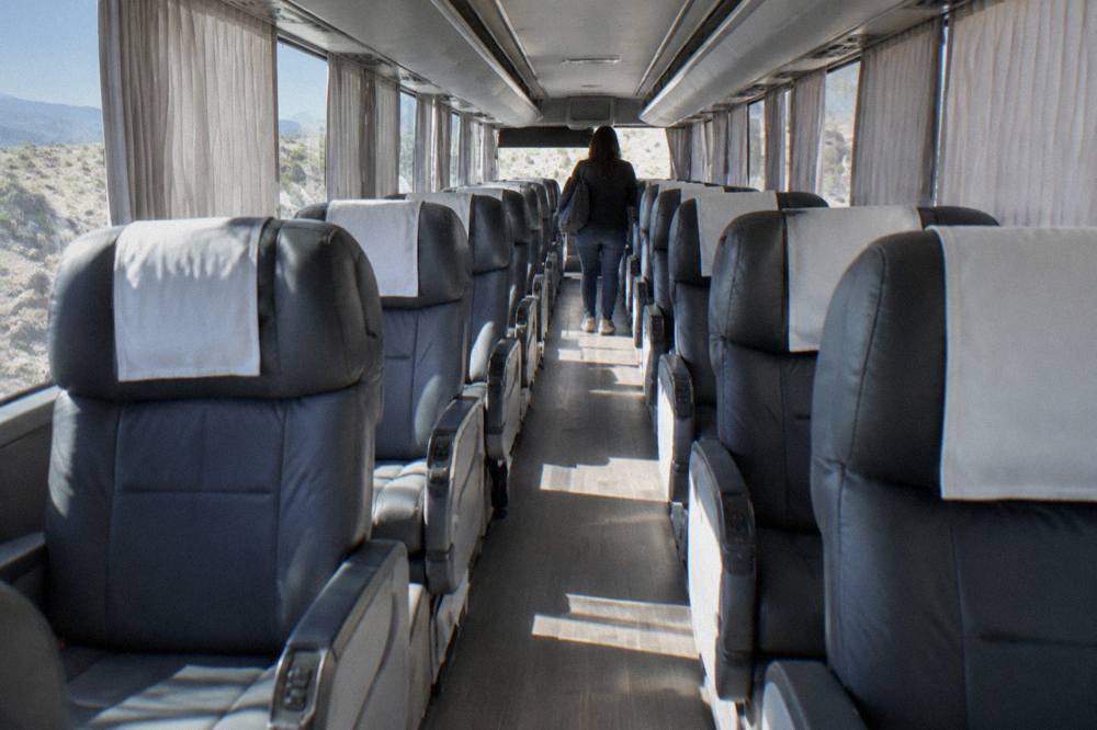 The interior of a modern first-class bus with reclining seats and curtains