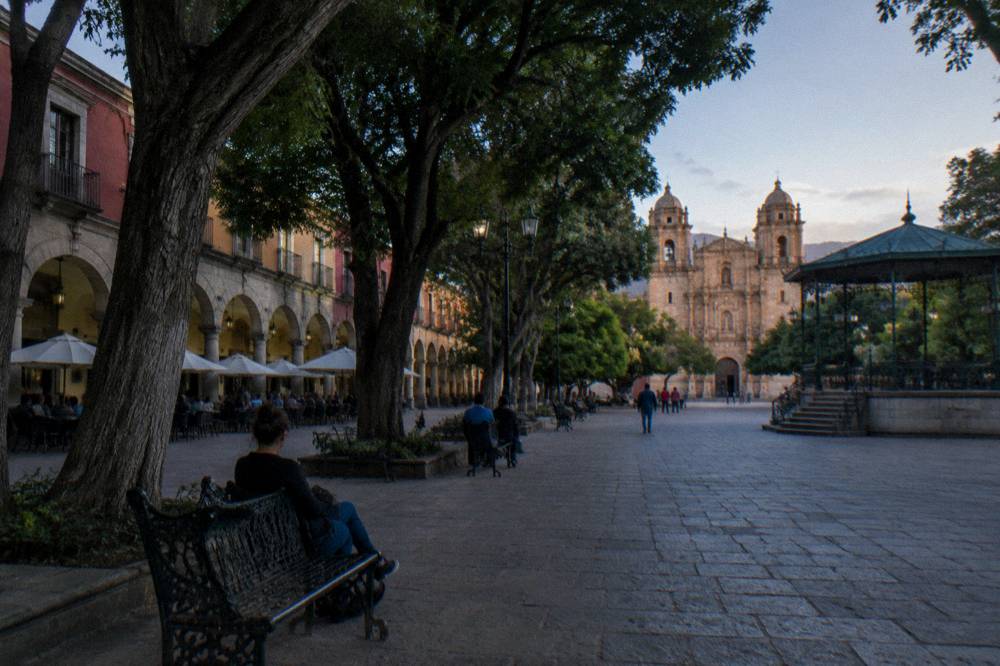 The shaded arcades of the Zócalo in Oaxaca City with people resting on benches