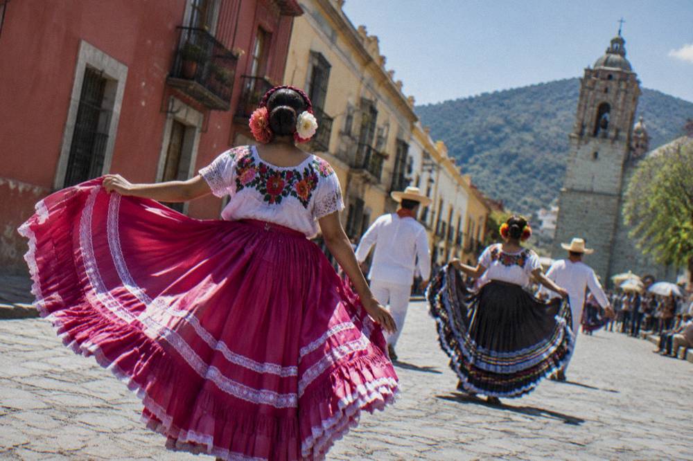 Dancers in traditional regional dress performing at an outdoor festival in Oaxaca
