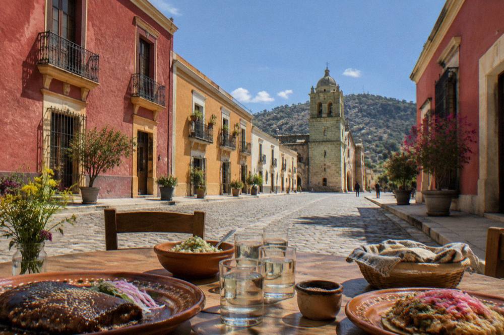 A courtyard table set with mezcal glasses and Oaxacan dishes
