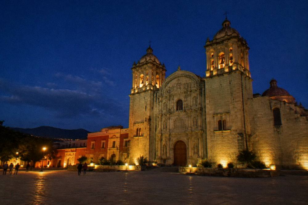 The green quarry stone facade of Santo Domingo church in Oaxaca at dusk