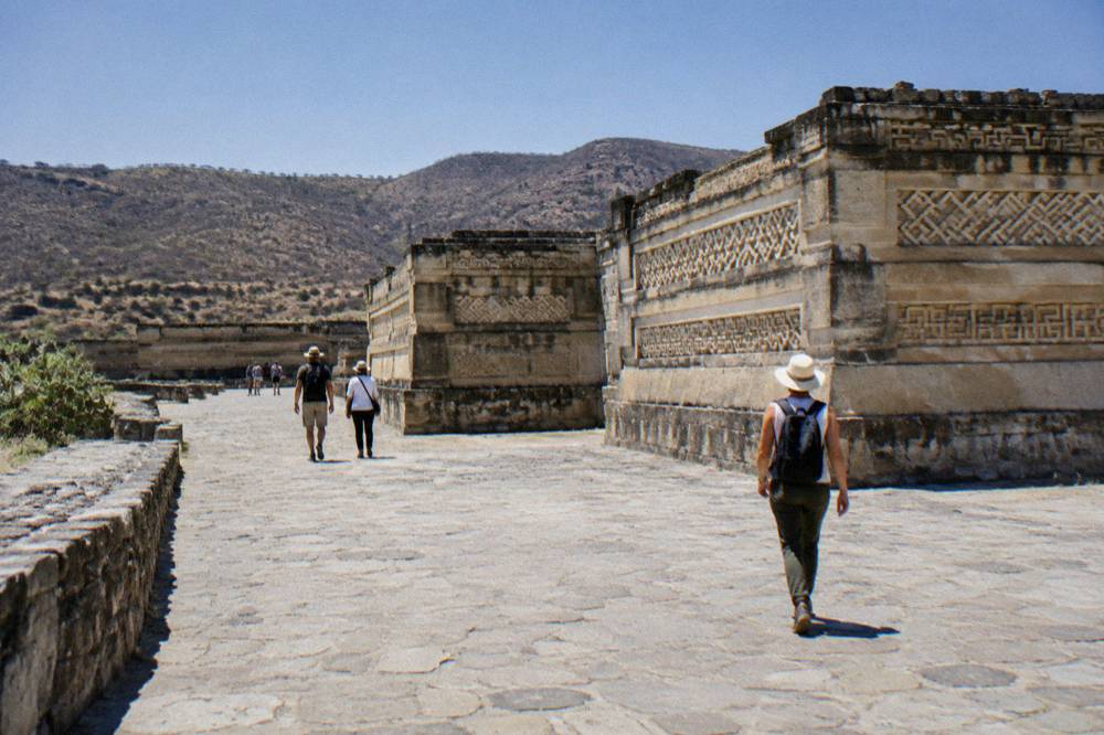 Visitors walking on a stone path at the Mitla archaeological site in Oaxaca