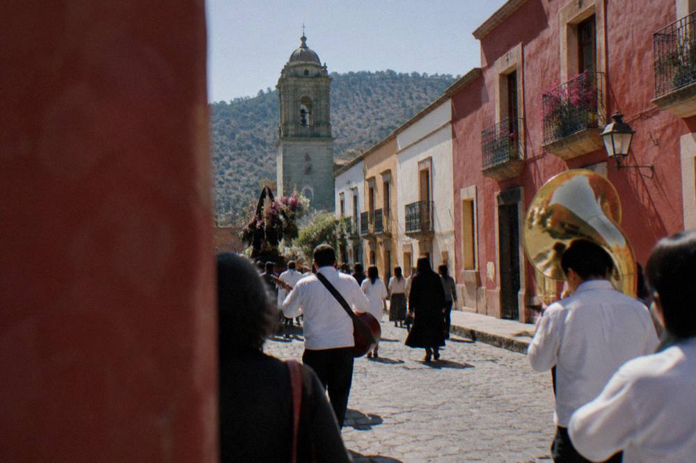 An evening procession with music moving through a decorated street in Oaxaca City