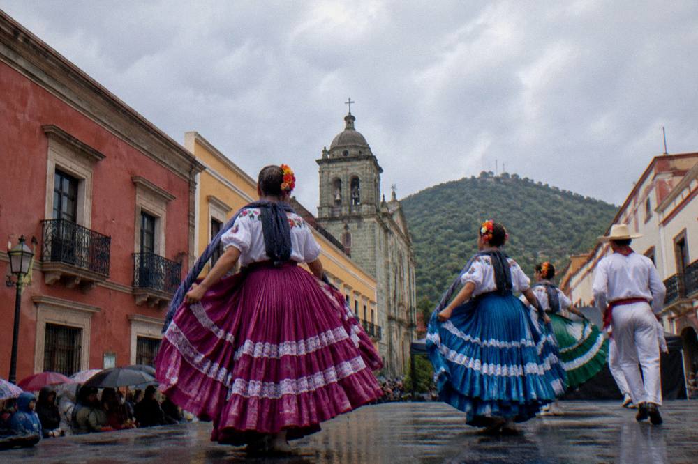 Dancers in regional dress performing on an outdoor stage during a summer festival