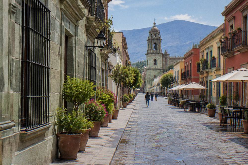 A pedestrian street in Oaxaca's historic centre lined with green cantera stone buildings and banners