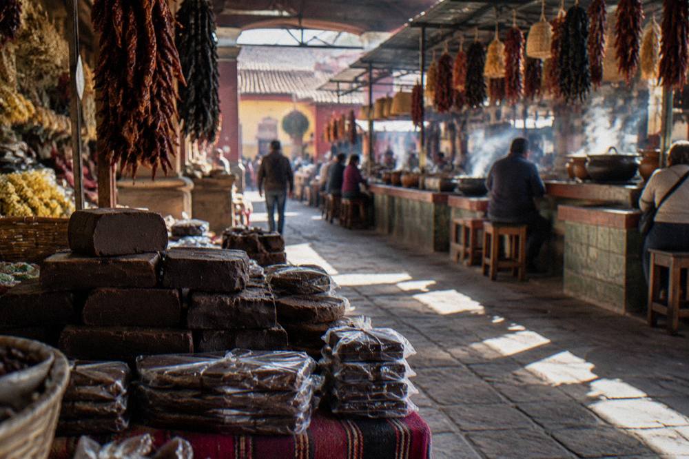 Wrapped blocks of dark chocolate paste stacked for sale at a market stall
