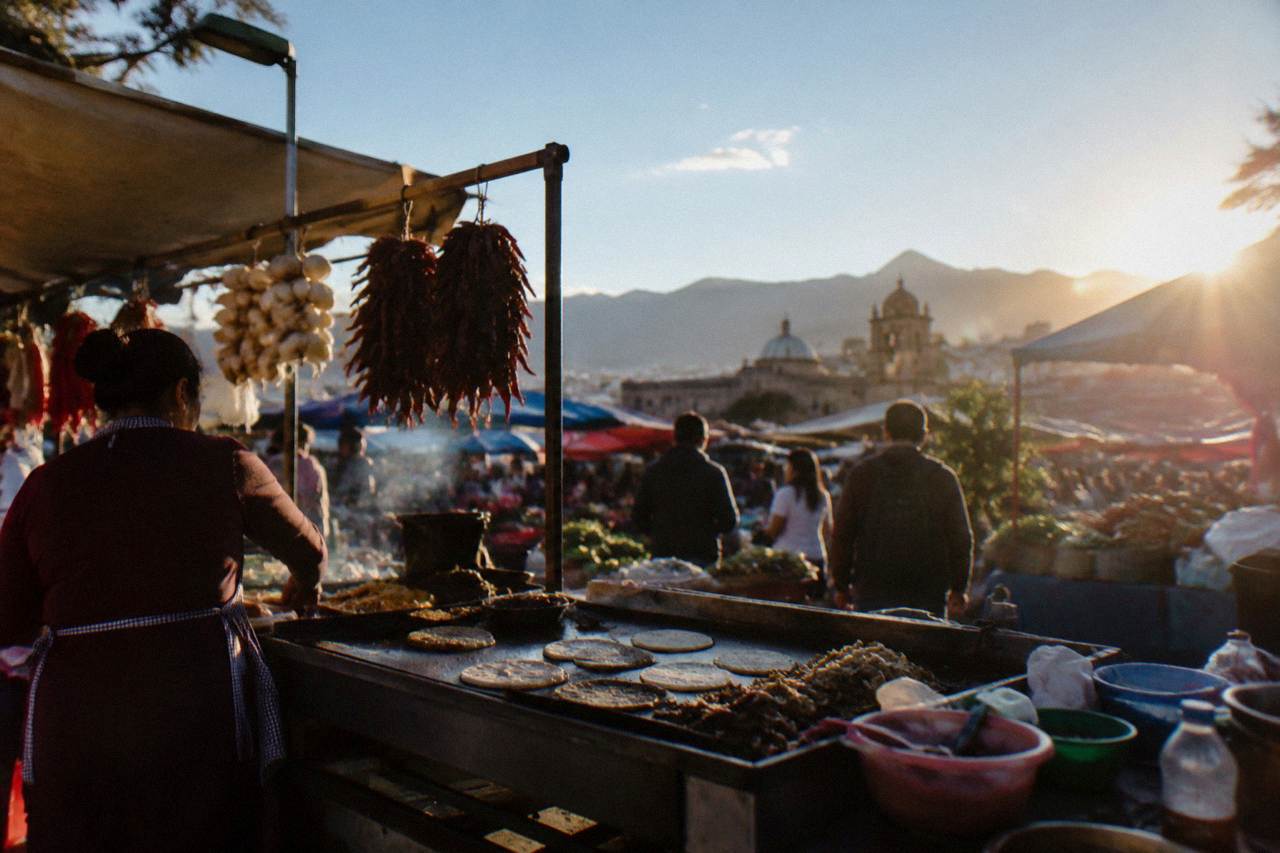 A busy market food stall in Oaxaca City with griddles and hanging ingredients