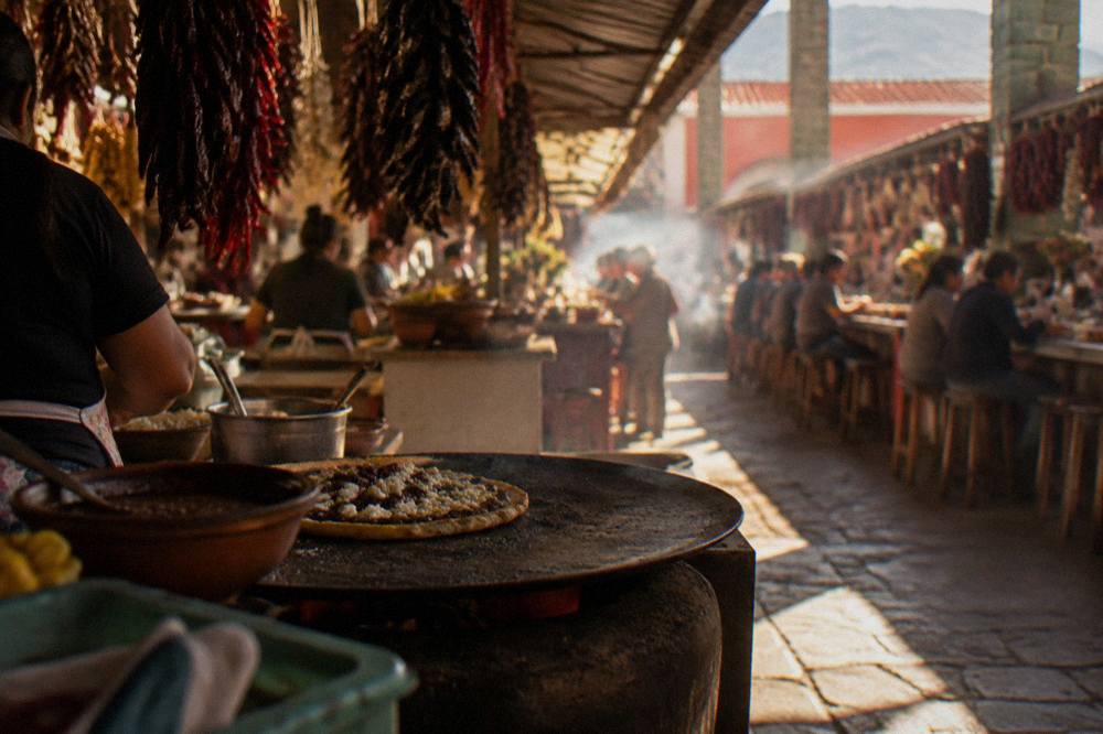 A memela cooking on a hot comal griddle at a market stall