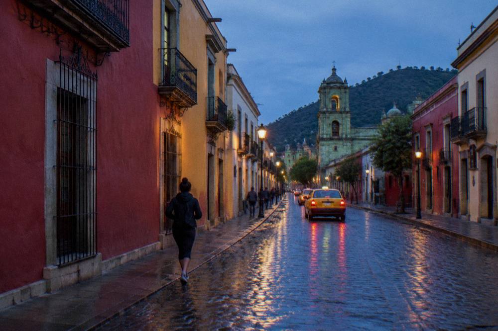 A taxi driving down a wet cobbled street in Oaxaca after afternoon rain