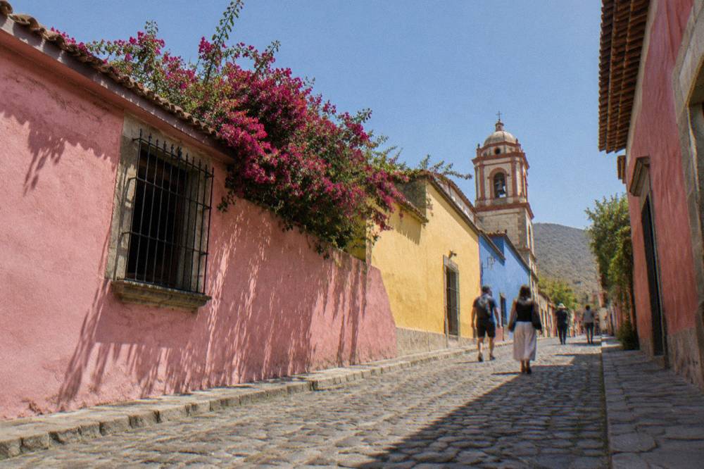 People walking a cobbled street with painted walls in the Jalatlaco neighbourhood