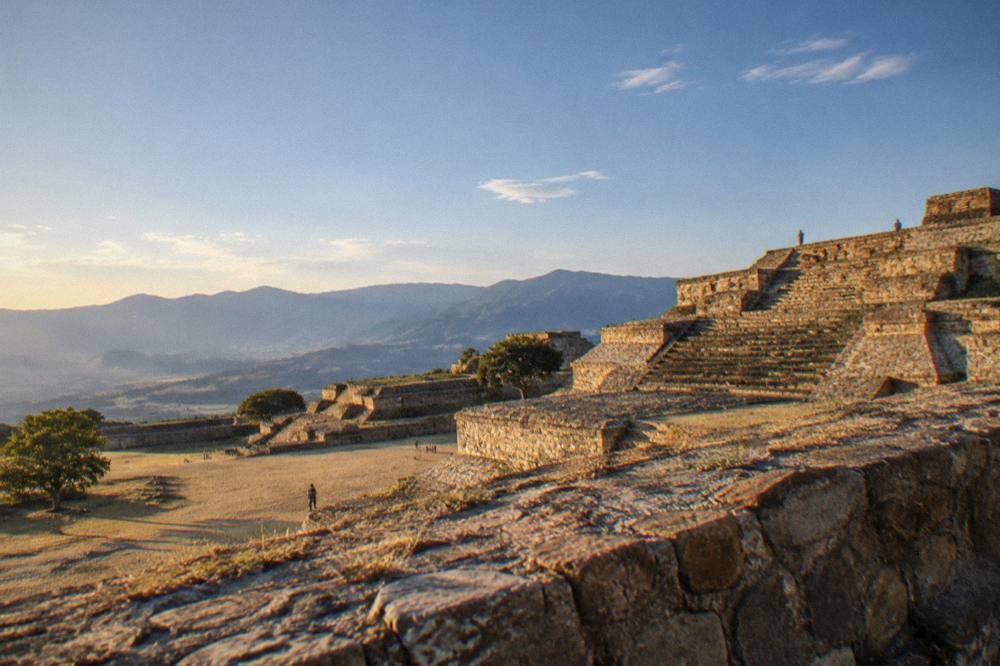 Stone terraces of the Monte Albán archaeological site on a hilltop under a blue sky
