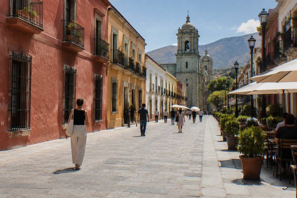 Pedestrians on the Andador Macedonio Alcalá pedestrian street with church towers behind