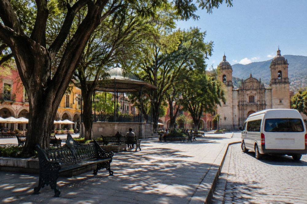 A shared colectivo van parked on a street with hills in the background