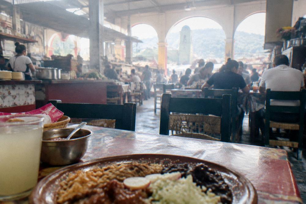 A busy market food hall in Oaxaca City with comedores serving plates at lunchtime