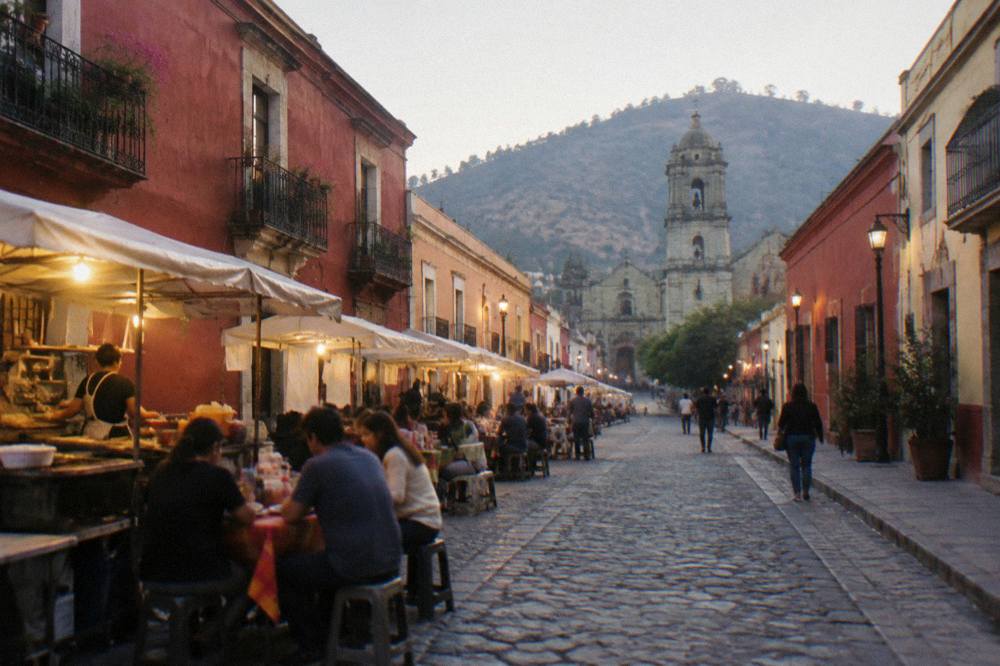 An evening street in Oaxaca City with food stalls lit and people eating at small tables
