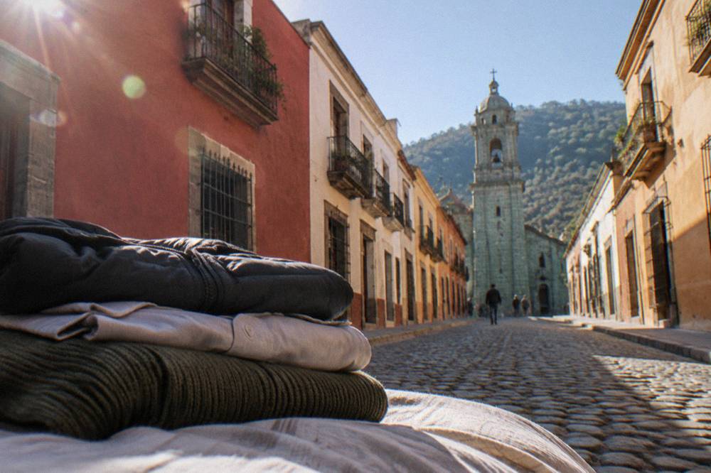 Folded layers arranged on a bed, including a sweater, a light shirt and a compact jacket