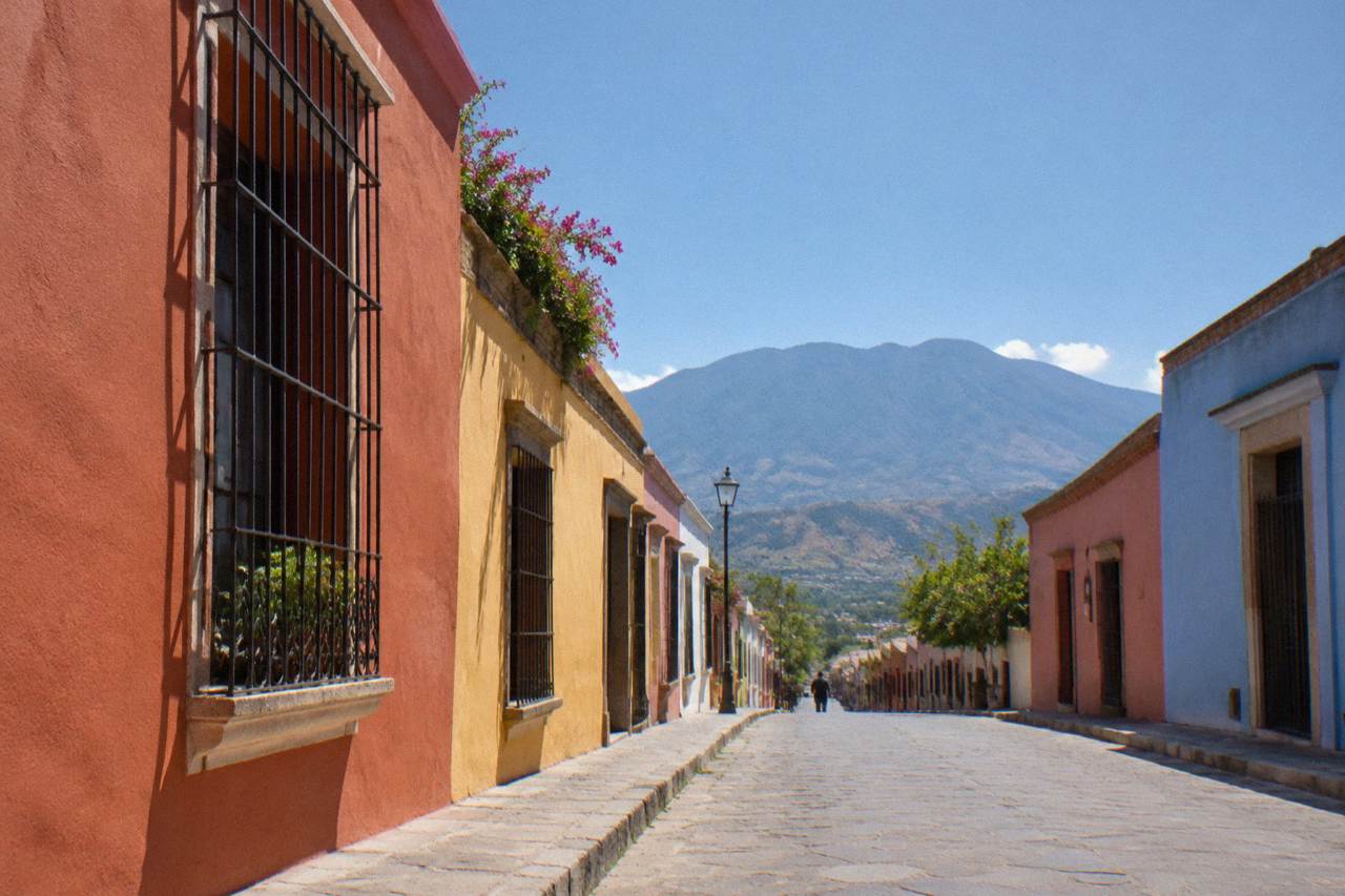 A quiet street of coloured houses in Oaxaca City with mountains in the distance