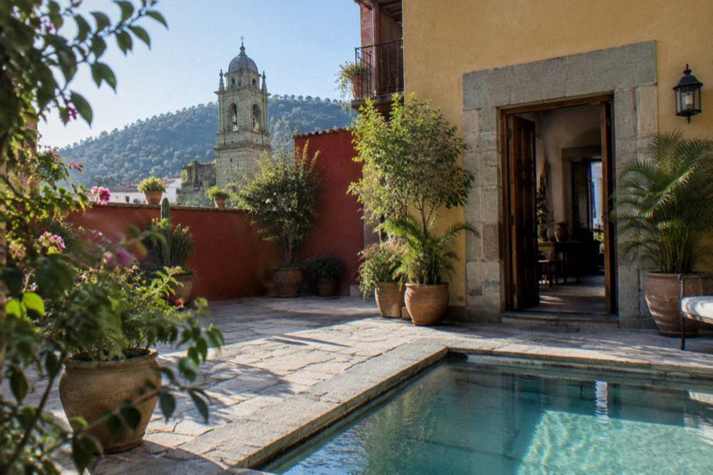 A hotel courtyard in Oaxaca with plants, stone floors and an open doorway