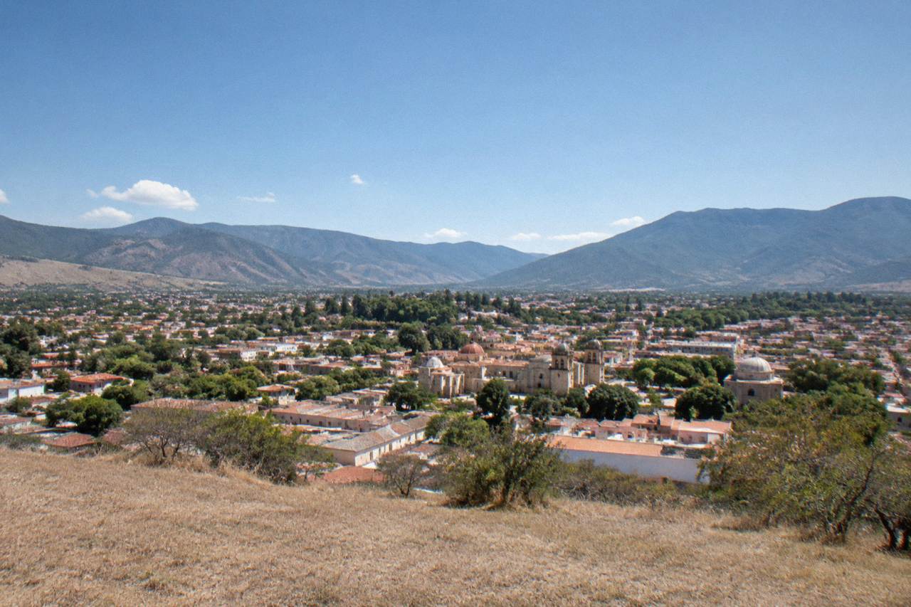 View over the rooftops and domes of Oaxaca City toward the surrounding mountains