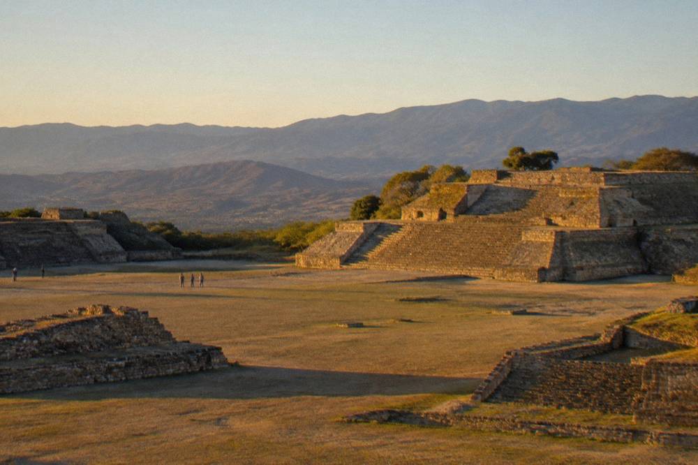 Ancient stone platforms and plaza of the Monte Albán archaeological zone under a clear sky