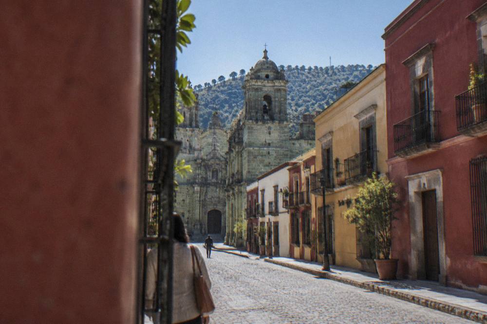Sunlit stone facade of a church in Oaxaca with green cantera detailing