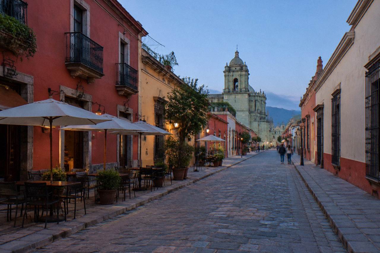 A quiet pedestrian street in Oaxaca City's historic centre with green stone buildings under a blue sky