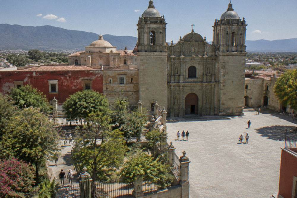 Visitors walking through the gated garden beside the Santo Domingo church complex in Oaxaca