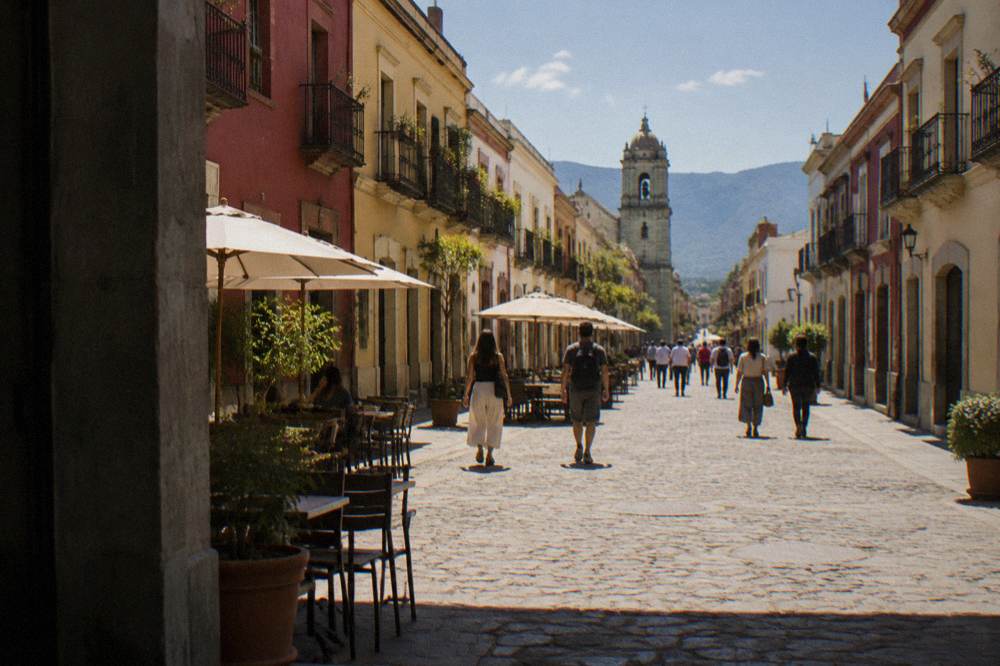 People walking along a lit pedestrian street in Oaxaca City's historic centre in the evening