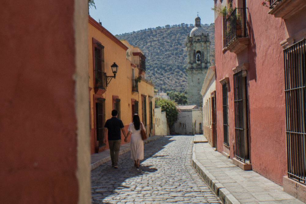 Two people walking hand in hand down a narrow colonial street with colourful walls