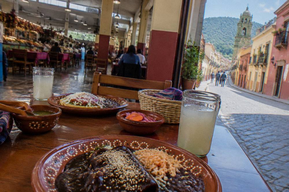 A table for two set with Oaxacan dishes and clay plates in a market dining hall