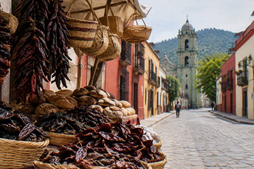 A market stall in Oaxaca with piles of dried chiles, bread and hanging baskets