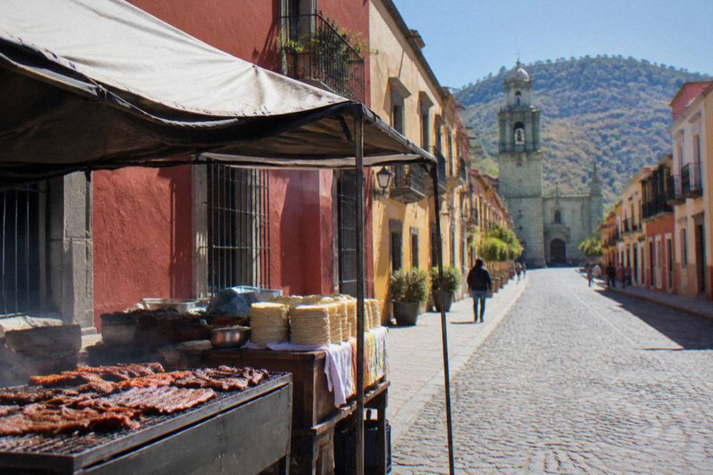 A market food stall with grilled meats and stacks of tortillas in Oaxaca