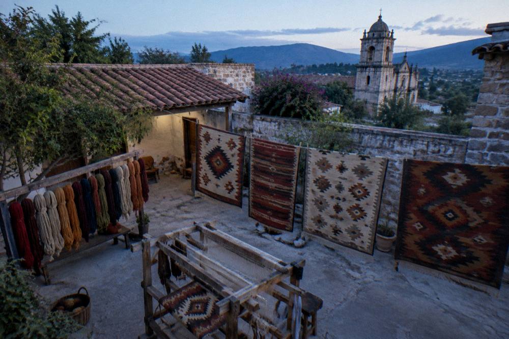 Handwoven wool rugs with natural dye patterns displayed in a workshop