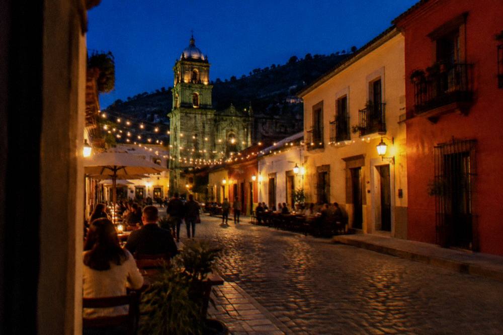 An evening street in Oaxaca City with string lights and people at outdoor tables