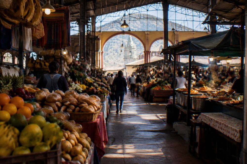 A busy covered market hall in Oaxaca with stalls of fruit, bread and cooked food