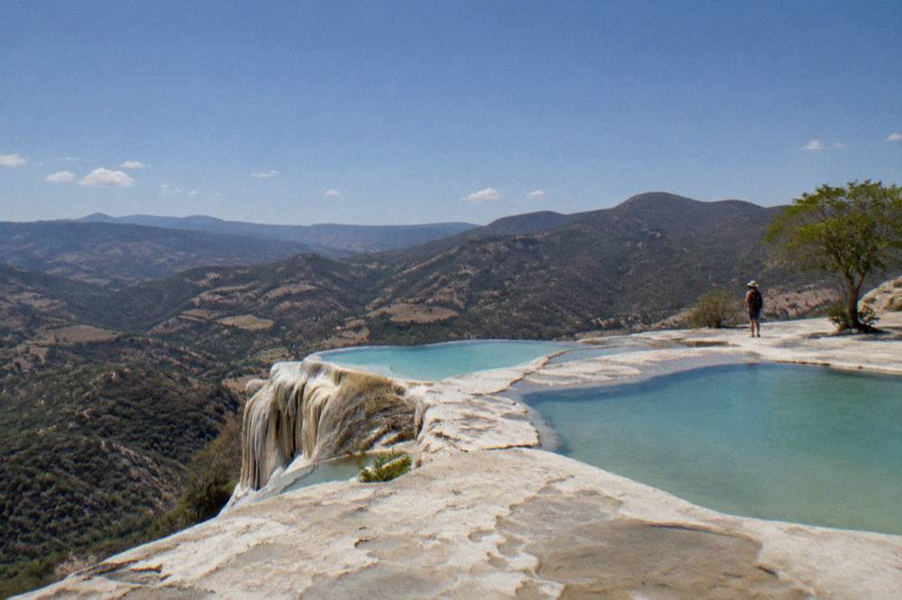 Mineral terraces of Hierve el Agua with turquoise pools at the cliff edge above a valley