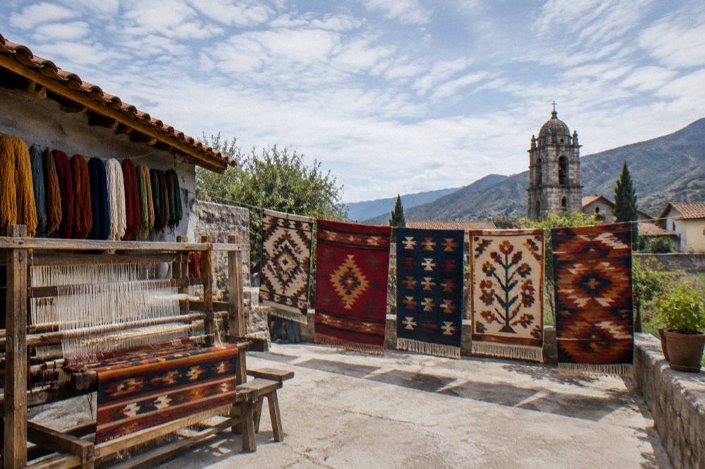 Colourful woven rugs hanging outside a workshop in a valley village