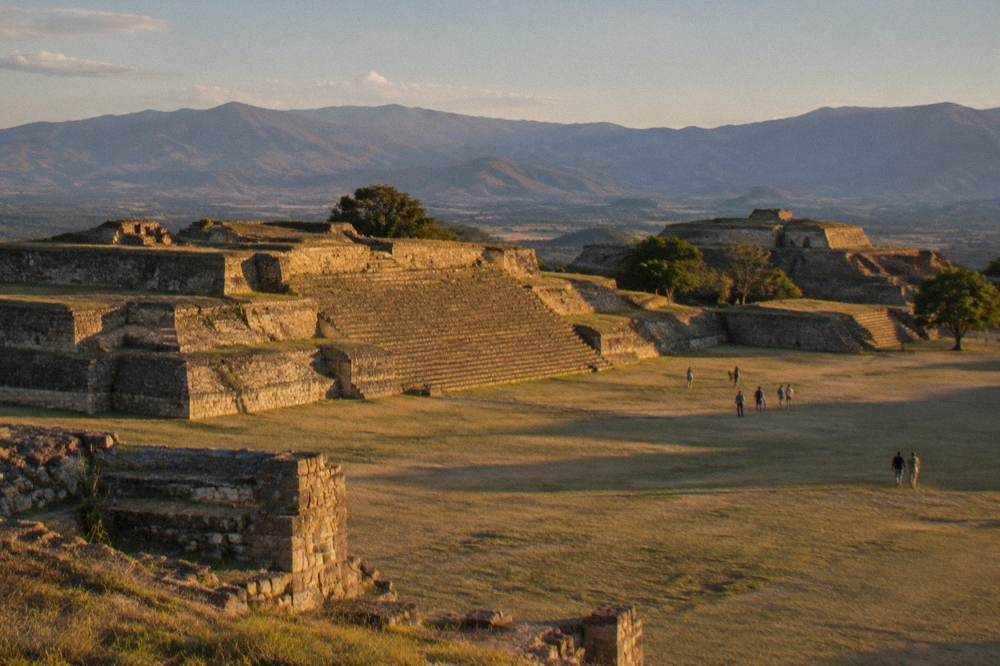 Ancient stone platform and grassy plaza of an archaeological site on a hillside