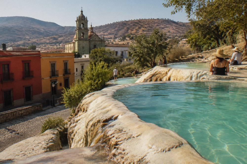 Mineral terraces and pools at a mountain spring above a valley