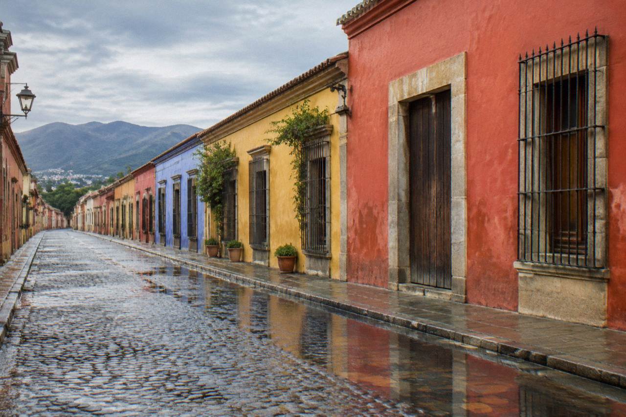 Wet cobblestones and painted facades after rain on a quiet street in Oaxaca City