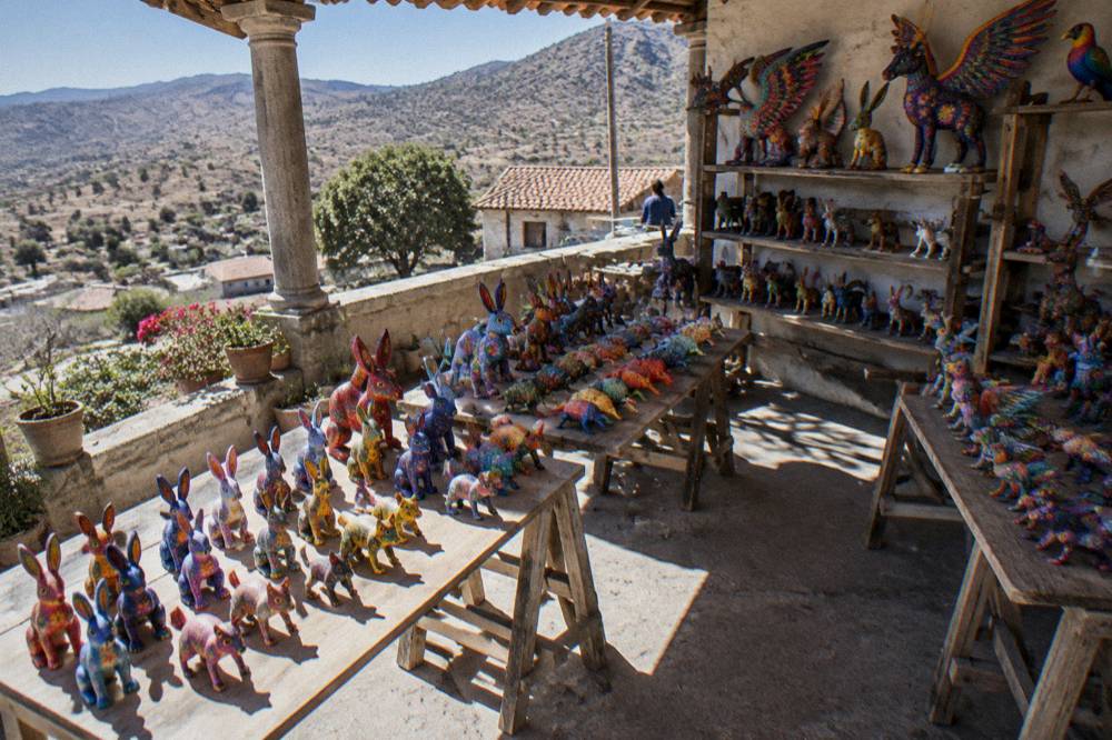 Brightly painted alebrije animal figures displayed on shelves in a workshop