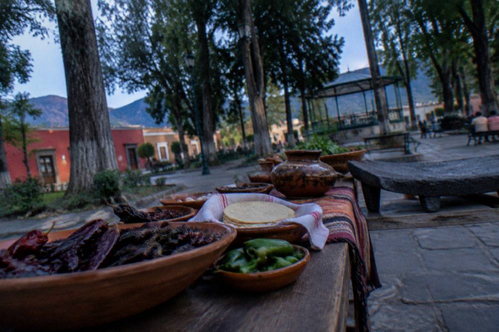 A cooking class table laid with chiles, tortillas and clay dishes ready for use