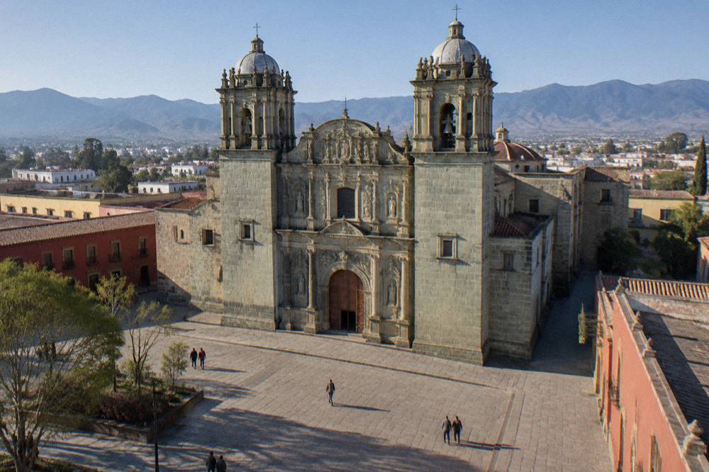 The green stone facade of Santo Domingo de Guzmán church in Oaxaca City under a clear sky