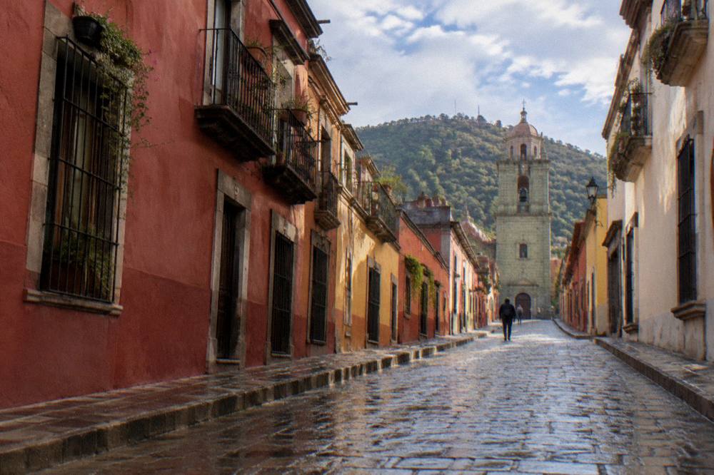 Stone paving shining with rain on a narrow Oaxaca street with coloured walls
