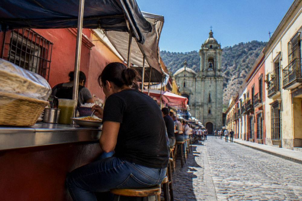 A single diner eating at a busy market stall counter in Oaxaca City
