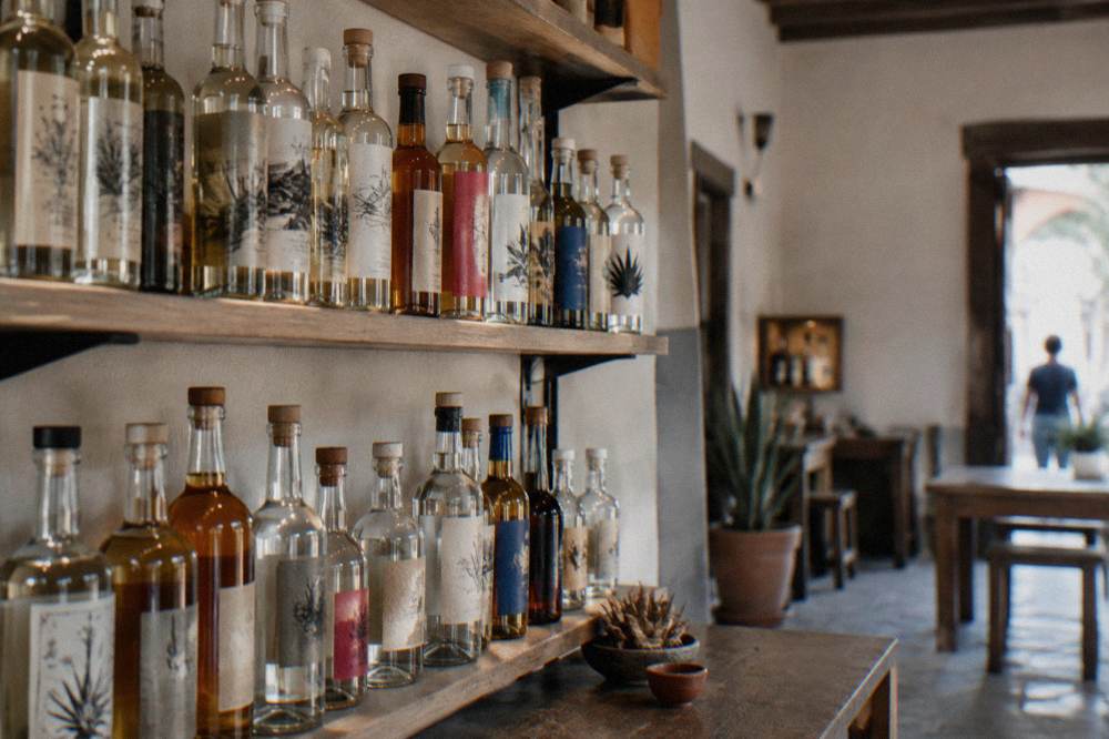 Bottles of mezcal lined up on a shelf in a tasting room in Oaxaca City's historic centre