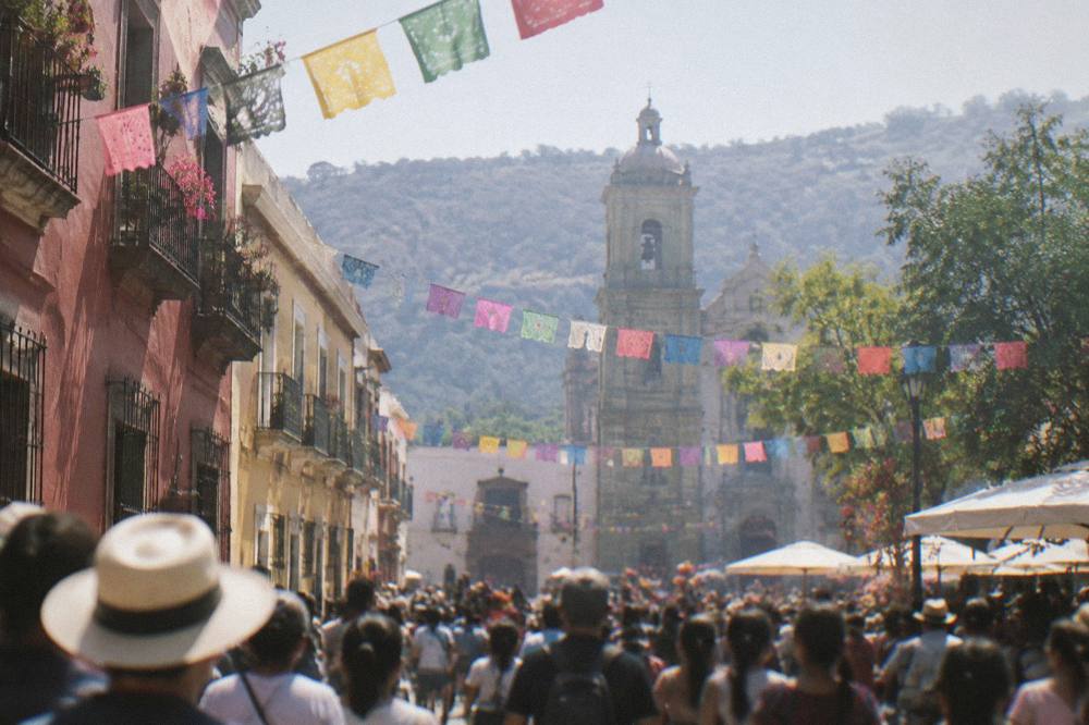 A crowded plaza in Oaxaca City during a festival with decorations overhead